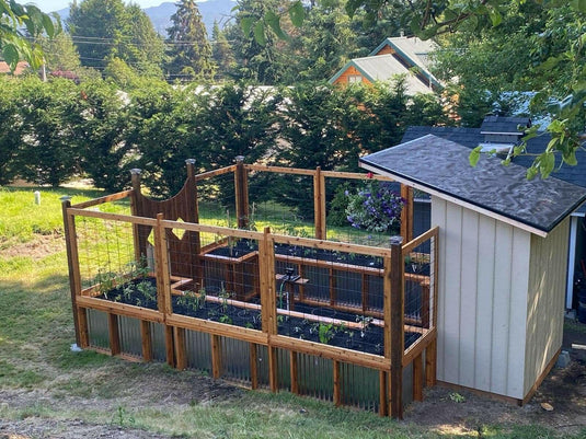 Black powder-coated hog wire fence enclosing vegetable garden