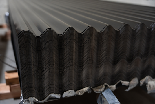 Stack of 26-gauge galvanized roofing sheets ready for landscaping install.