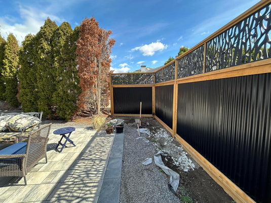 Corrugated metal fence with hog wire toppers in modern residential backyard