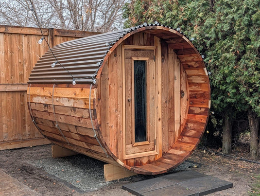 Western red cedar barrel sauna with a corrugated metal roof